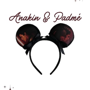 Könnte beinhalten: Schwarzes Mausohren-Stirnband mit Bildern von Anakin und Padmé. Die Ohren sind mit schwarzen Schleifen verziert. Der Text "Anakin & Padmé" ist in Burgunder-Schrift geschrieben. Ein lustiges Accessoire für Fans der Star Wars-Saga.