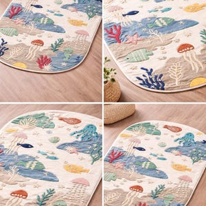 May include: Oval rug with an underwater scene design. The rug features a cream-colored background with blue, green, yellow, and red sea creatures and coral. The design includes fish, jellyfish, and an octopus.