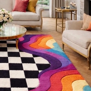 May include: A rectangular area rug featuring a black and white checkered pattern on one side and a series of vibrant, multi-colored wavy stripes in shades of purple, magenta, orange, yellow, and blue on the other side with a textured surface.