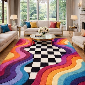 May include: A rectangular area rug featuring a central black and white checkered pattern surrounded by thick, wavy bands of vibrant colors including red, orange, yellow, blue, and purple. The rug has a textured, plush pile surface throughout.