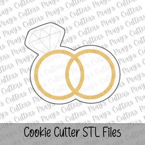 Puede incluir: Un cortador de galletas con la forma de dos anillos de boda y un anillo de compromiso con diamantes. Los anillos son de color dorado y el anillo de diamantes tiene un diseño geométrico. El texto "Cookie Cutter STL Files" está en la parte inferior.