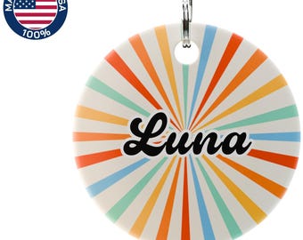May include: A round, white keychain with a colorful, retro sunburst design in orange, yellow, blue, and green. The name "Luna" is written in black script across the center. A metal ring is attached at the top. The words "Made in the USA" and the American flag are in the upper left corner.