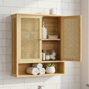 Peut inclure: Un meuble de salle de bain en bois clair avec un panneau de porte tissé. L'armoire a deux étagères, l'une avec des serviettes blanches roulées et une petite plante en pot. L'autre étagère contient des articles de toilette.