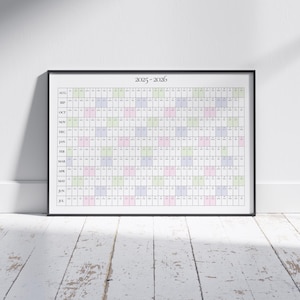Op de afbeelding: Een ingelijste kalender voor 2025-2026, met een rasterindeling die maanden en dagen weergeeft. De zwart omlijste kalender staat tegen een witte muur. Het raster gebruikt pastelkleuren voor visuele organisatie.