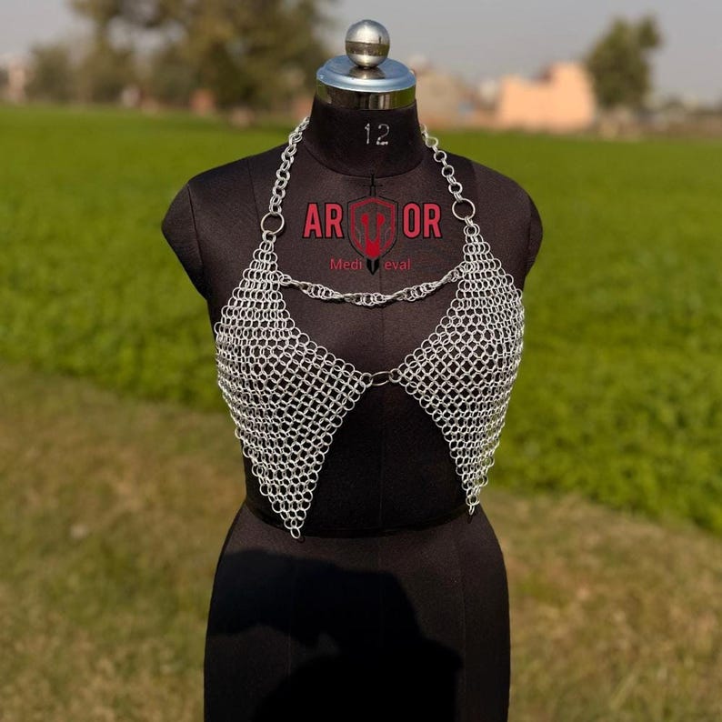 A close-up of the silver chainmail halter top featuring connected triangular panels on a black dress form.