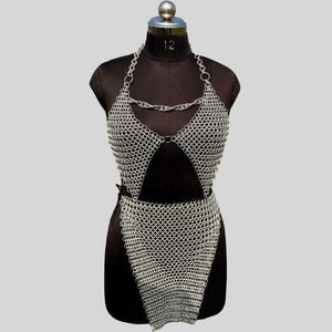 A silver chainmail top and skirt set displayed on a black dress form against a light grey background.