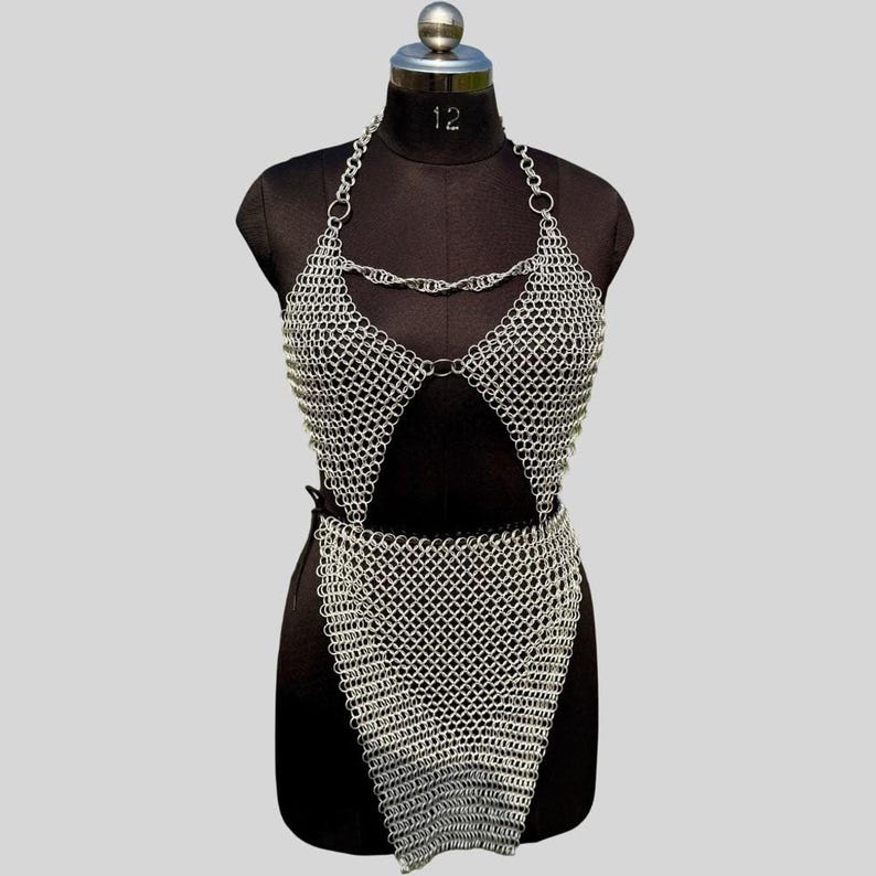 A silver chainmail top and skirt set displayed on a black dress form against a light grey background.