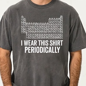 May include: Dark gray t-shirt with a white periodic table design and the text "I WEAR THIS SHIRT PERIODICALLY." The shirt is made of a soft material and has short sleeves. The shirt is a relaxed fit.
