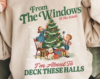 May include: Cream-colored sweatshirt with a vintage Christmas graphic. The design features a decorated Christmas tree, children, a dog, and the text "From The Windows To The Walls" and "I'm About To Deck These Halls".