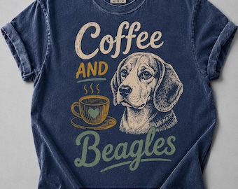 May include: A navy blue short-sleeve t-shirt featuring a graphic print of a beagle dog and a coffee cup. The text reads Coffee AND Beagles. The shirt has a crew neckline and a vintage-style washed finish, with a Comfort Colors brand label at the neck.