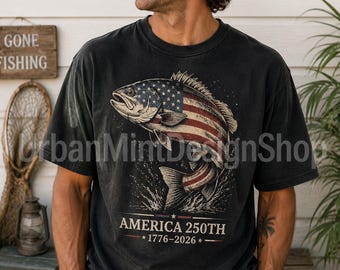 May include: A black short-sleeve t-shirt featuring a graphic of a fish with a United States flag pattern on its body. Below the fish, the text reads AMERICA 250TH 1776-2026 with stars and horizontal lines. The design has a distressed, vintage appearance.