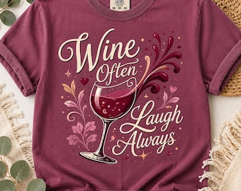 May include: A maroon t-shirt with the words "Wine Often Laugh Always" in a decorative font. The graphic includes a wine glass filled with red wine, floral accents, and the text "Option 1" at the bottom.