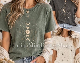 Puede incluir: Tres camisetas de manga corta y cuello redondo en verde oliva, gris carbón y crema. Cada camiseta presenta un estampado gráfico celestial con fases lunares, estrellas y elementos planetarios. El texto UrbanMintDesignShop es visible en la camiseta oliva.