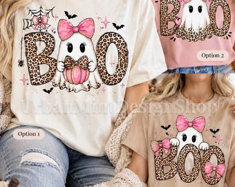 May include: Three short-sleeve t-shirts featuring Halloween-themed graphics. Each shirt displays a white ghost character with a pink bow, leopard print lettering spelling BOO, and small black bats. The designs include pink accents and spiderwebs.