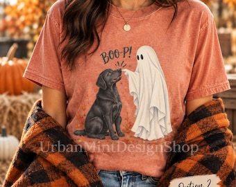 May include: A rust-colored short-sleeve t-shirt featuring a graphic of a black Labrador dog and a white ghost. The ghost is touching the dog's nose, with the text BOO-P! printed above them. The shirt has a vintage-style washed appearance.