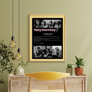 May include: A framed print with a black background and gold frame. The print features the word "LOVE" in white, the text "Happy Anniversary" in pink, and a black and white photo collage. The text "To the person who holds my heart and soul" is also included.