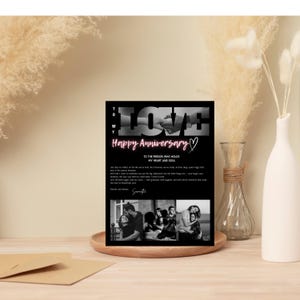 May include: A black and white anniversary card with the word "LOVE" in large letters and the words "Happy Anniversary" in pink. The card includes a message and three black and white photos. The card is displayed on a wooden tray.