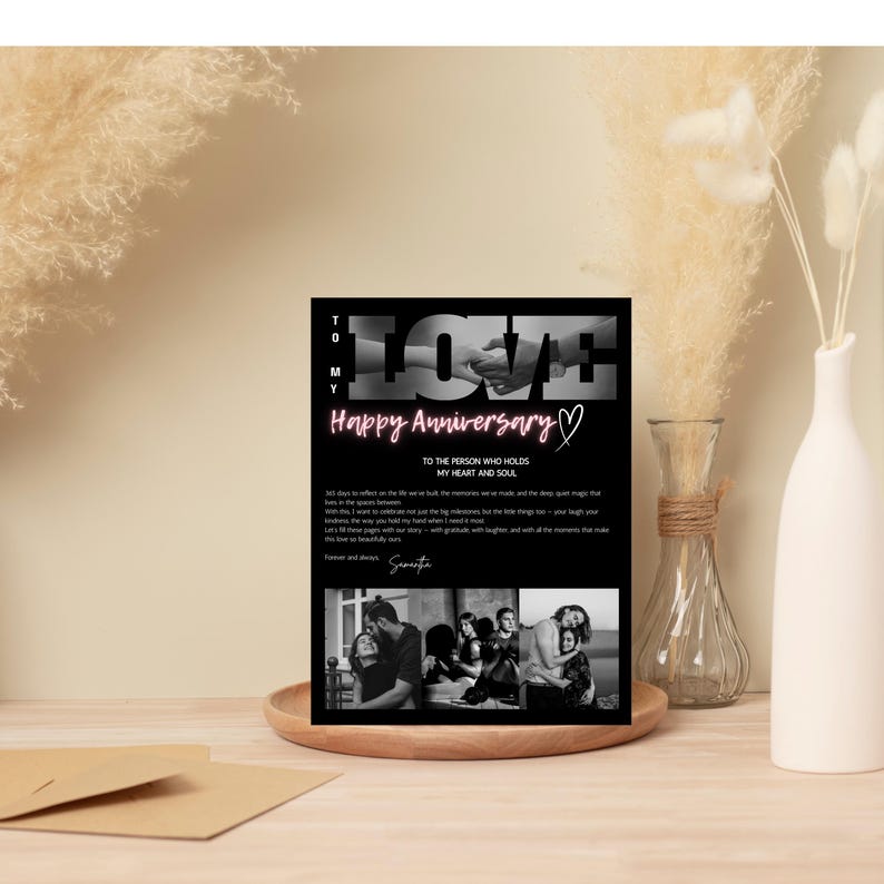 May include: A black and white anniversary card with the word "LOVE" in large letters and the words "Happy Anniversary" in pink. The card includes a message and three black and white photos. The card is displayed on a wooden tray.