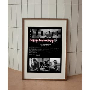 May include: A framed print with a black background and the word "LOVE" in white. The text "Happy Anniversary" is in pink neon. Below are black and white photos of a couple. The print is in a brown wooden frame.