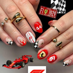 May include: A set of manicured nails with a Formula 1 theme. The nails feature red, white, and black designs, including racing flames, checkered patterns, and the Ferrari logo. Gold rings and a Formula 1 race car are also visible.