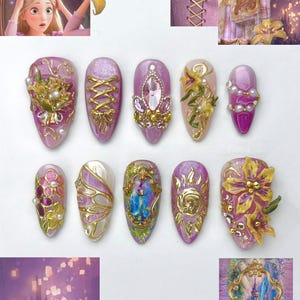 May include: A set of ten press-on nails featuring purple and gold designs inspired by Rapunzel. The nails are decorated with 3D gold accents, pearls, pink rhinestones, floral motifs, corset lacing patterns, a sun emblem, and a miniature ornate gold frame.