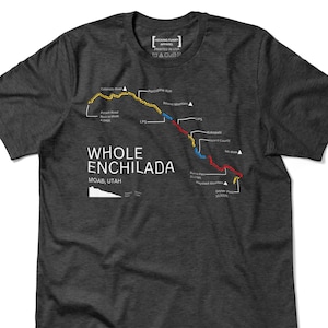 May include: Dark gray t-shirt with a map graphic of the Whole Enchilada trail in Moab, Utah. The map features a colorful trail route with text labels like "Colorado River" and "Porcupine Rim". The shirt also has the text "HECKING FUNNY APPAREL PRINTED IN USA".