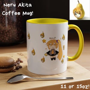 May include: White coffee mug with a yellow interior and handle. The mug features a cartoon character and pear illustrations. Text on the mug reads "Neru Akita Coffee Mug!" and "11 or 15oz!". A spoon and a macaron are in the foreground.