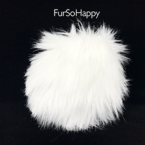 May include: A fluffy, white faux fur pompom against a black background. The pompom is round and has long, soft, and spiky fibers. The text "FurSoHappy" is in white letters in the upper left corner.