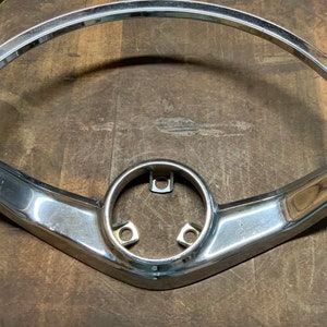 May include: A chrome steering wheel frame for a classic car. The frame is in good condition and has a smooth, shiny finish.