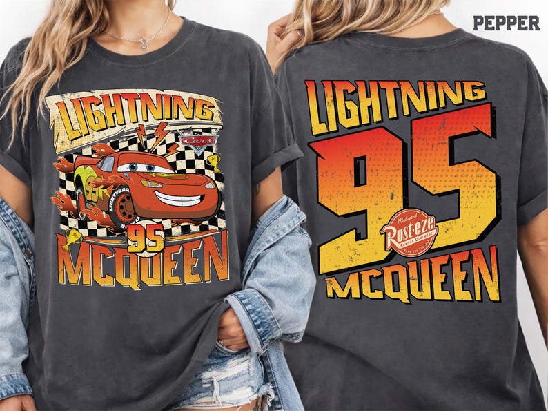 May include: Dark grey t-shirt featuring Lightning McQueen from the Cars film. The front graphic includes McQueen, the number 95, and the text "Lightning" and "McQueen". The back of the shirt displays "Lightning 95 McQueen".
