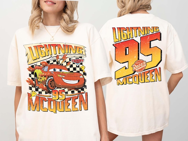 May include: A cream-coloured t-shirt with a graphic of Lightning McQueen from the film Cars. The front design features "Lightning McQueen 95" with a chequered flag background. The back of the shirt displays "Lightning 95 McQueen" in a gradient orange and yellow.
