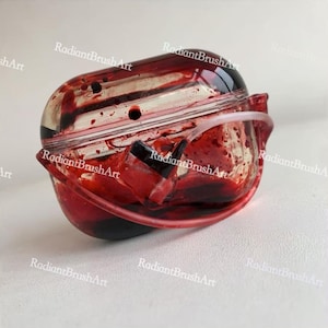 Op de afbeelding: Een helder, afgerond object met een rode, bloedachtige substantie erin. Het object heeft een gebogen, transparante handgreep en een zwart accent. De tekst "RadiantBrushArt" is zichtbaar.