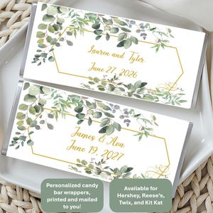 May include: Two rectangular candy bar wrappers featuring a white background with watercolor green eucalyptus leaves and a gold geometric frame. The top wrapper displays the text Lauren and Tyler June 27, 2026, and the bottom displays James & Ava June 19, 2027.