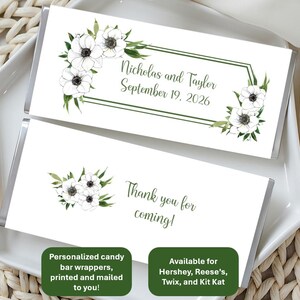 May include: Two candy bar wrappers with white anemone floral designs. One wrapper reads "Nicholas and Taylor September 19, 2026" within a green frame. The other says "Thank you for coming!" with a floral accent. The wrappers are on a white plate.