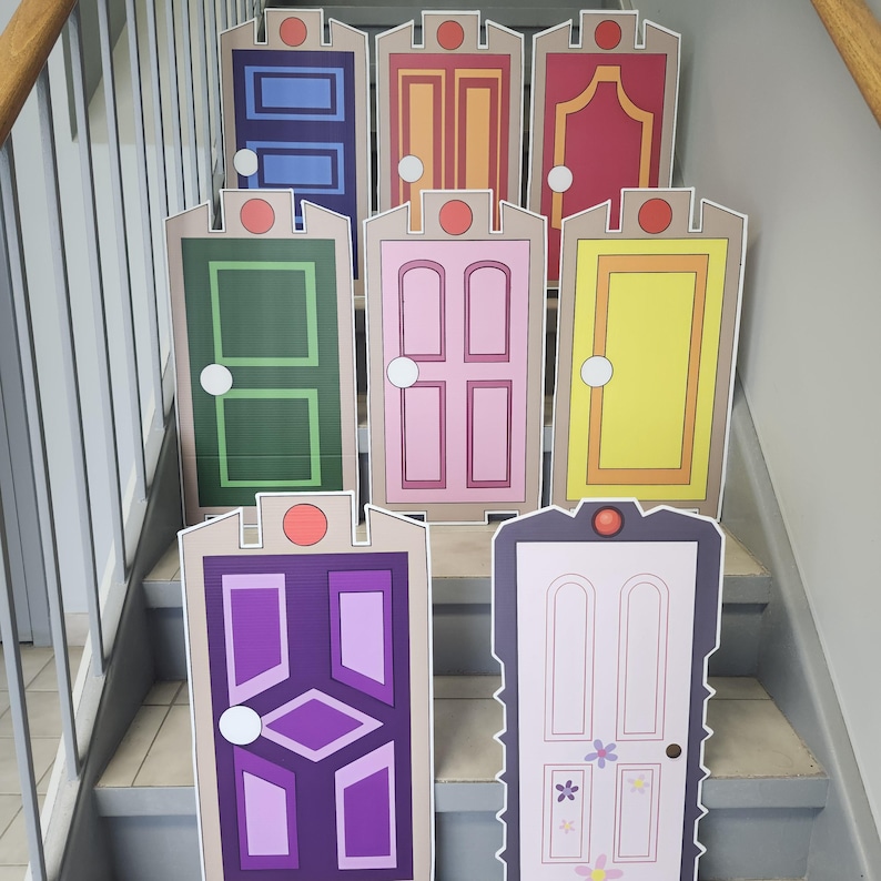 May include: A collection of colorful, cartoon-style door cutouts arranged on a staircase. Each door features a unique design and color scheme, including blue, pink, green, and yellow, with a circular accent at the top. The doors are likely themed for a children's party or event.