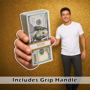 May include: A stack of one hundred dollar bills secured with a white and gold band labelled $10,000 ONE HUNDREDS. The stack features a grip handle for holding. The currency displays the portrait of Benjamin Franklin and the text 100.