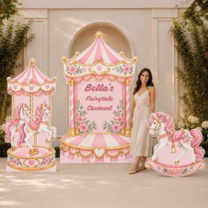 May include: A set of three large carousel-themed party decorations featuring pink and white striped canopies, floral accents, and gold trim. The central display includes the text Bella's Fairytale Carousel in pink script lettering.
