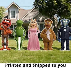 May include: Cardboard cutouts of five Muppet characters: Animal, Kermit the Frog, Miss Piggy, Fozzie Bear, and Gonzo, standing on a grassy lawn in front of a house. The text "Printed and Shipped to you" is at the bottom.