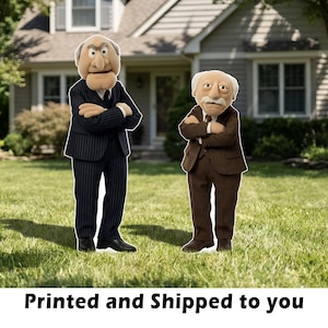 May include: Two puppet figures, one in a pinstripe suit and the other in a brown suit, stand on a grassy lawn in front of a house. The text "Printed and Shipped to you" is at the bottom of the image.