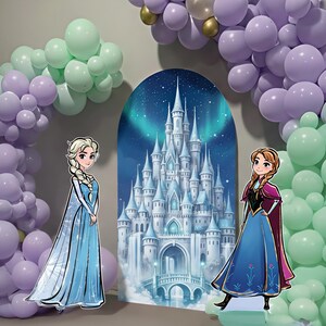 May include: A party scene featuring a backdrop of a castle with a night sky and aurora borealis. Two cardboard cutouts of cartoon characters stand in front of the backdrop. The scene is decorated with balloon arches in shades of purple, green, and gold.