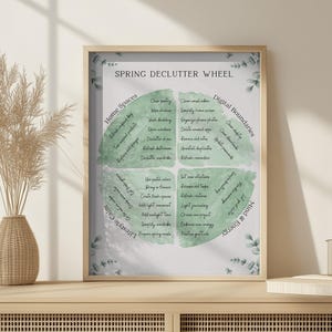 May include: A framed print titled "Spring Declutter Wheel" with a light wood frame. The print features a circular design with green watercolor accents and text outlining decluttering tasks for home, digital, lifestyle, and mind & energy.