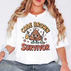 May include: White t-shirt with a cartoon graphic of a smiling poop character wearing a nurse's hat, holding a spray bottle and a broom. The text "CODE BROWN SURVIVOR" is above and below the character in orange and yellow.