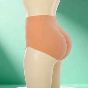 May include: A peach-colored, high-waisted undergarment designed to enhance the wearer's figure. The garment is displayed on a mannequin against a light green backdrop. The undergarment is smooth and seamless, with a focus on the rear.