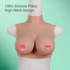 May include: A flesh-toned silicone breast form with a high-neck design. The form has two breasts with heart-shaped stickers over the nipples. The text "100% Silicone Filled High-Neck Design" is printed on the top.