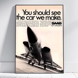 May include: A framed vintage advertisement poster featuring a black and white photograph of a jet aircraft on a runway. The text reads: You should see the car we make. SAAB is the only car in the world made by a manufacturer of advanced jet aircraft.