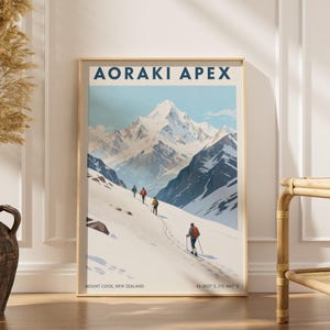 Peut inclure: Une affiche encadrée intitulée "AORAKI APEX" représente une scène de montagne enneigée avec des skieurs et des randonneurs. L'œuvre présente un ciel bleu clair, des sommets enneigés et un cadre en bois. Le bas de l'affiche indique "Mount Cook, New Zealand" et des coordonnées.