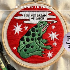 May include: An embroidery hoop with a red background and a green frog design, with the text "I DO NOT DREAM OF LABOR". The image includes embroidery floss and scissors. The text "BEGINNER FRIENDLY" and "PDF Embroidery Pattern & Tutorial" are also visible.