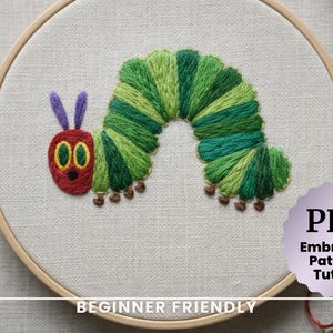 May include: Embroidered caterpillar design in a wooden hoop. The caterpillar is green and red with purple antennae and brown feet. The text "PDF Embroidery Pattern & Tutorial" is visible, along with "Beginner Friendly".
