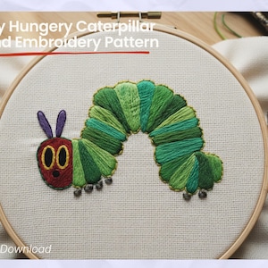 May include: Hand embroidery pattern featuring a colorful caterpillar design. The caterpillar is stitched with shades of green and red thread, set against a white fabric background within a wooden embroidery hoop. Text reads "Very Hungry Caterpillar Hand Embroidery Pattern".