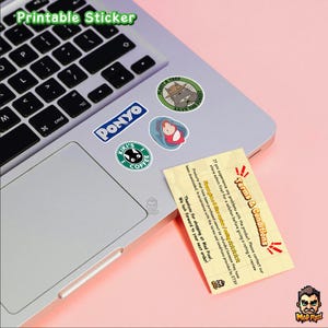 May include: A laptop with several colorful stickers featuring cartoon characters and the text "Printable Sticker." The stickers include a Totoro design, a "Ponyo" sticker, and a "Kiki's Coffee" sticker. A business card with "Terms & Conditions" is also visible.